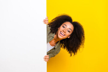 Photo of friendly nice girl with perming coiffure wear khaki shirt look out of offer on empty space isolated on yellow color background