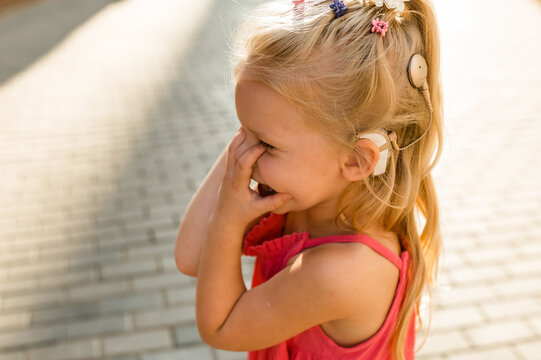 Funny baby with cochlear implant walks outdoor. Hearing aid and medicine innovating technology concept. Diversity and inclusion and people with disability concept. Copy space