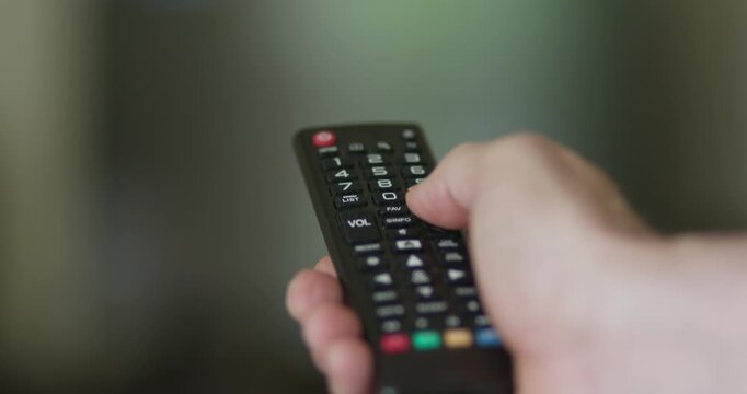 closeup of man using a remote control for his TV