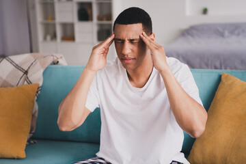 Photo of stressed depressed guy nightwear pajama sitting couch feeling bad indoors room home house