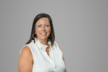 Headshot of Caucasian brunette middle age business woman in studio on gray backdrop