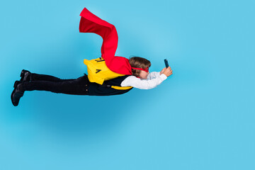 Full body portrait of little schoolchild boy superhero costume uniform smart phone fly isolated on...