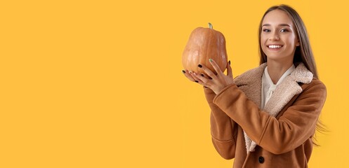 Naklejka premium Pretty young woman holding pumpkin on yellow background with space for text