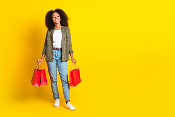 Full size photo of dreamy girl wear khaki shirt hold shopping bags look at discount empty space isolated on yellow color background