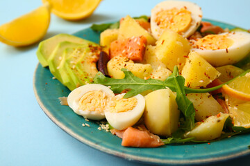 Plate of tasty potato salad with eggs and avocado on light blue background, closeup