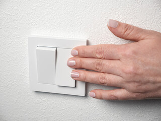 Woman switch on the light at home. Female hand push button on wall