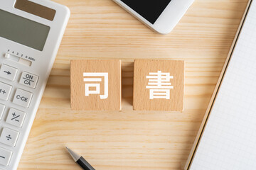 司書の文字が入ったブロック、電卓、スマホ、ノート