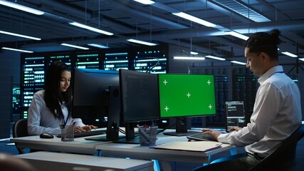 Programmer overseeing data center using isolated screen computer, ensuring system can handle...