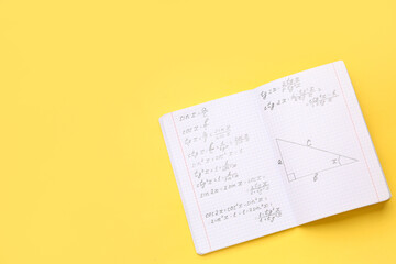 Copybook with maths formulas on yellow background