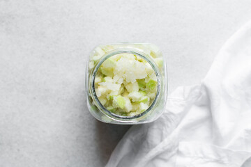 Overhead view of apple cheong in a glass jar on a white background, top view of korean apple cheong...
