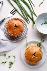 Plates with tasty meat pot pies on light background © Pixel-Shot