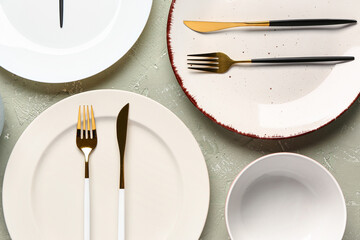 Table setting with clean plates, bowls and cutlery on grey grunge table