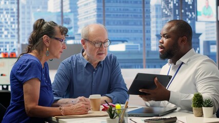 Senior citizens meeting with a financial advisor to plan their retirement, discussing pension plans and savings growth. Establishing financial goals with agency broker consultant. Camera A.