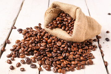 Bag with coffee beans on light wooden background