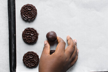 Overhead view of stamped chocolate cookies on a parchment lined baking tray, top view of embossed chocolate sugar cookies on a white background