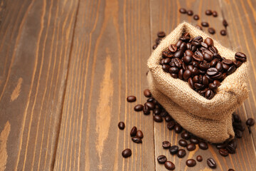 Bag with coffee beans on wooden background