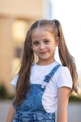 Smiling little girl is having fun walking down the street. Urban lifestyle concept. City background.