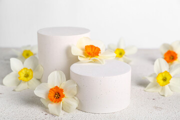 Decorative plaster podiums with flowers on grunge table against white background
