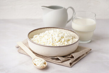 Bowl with tasty cottage cheese on light background