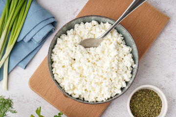 Bowl with tasty cottage cheese on light background