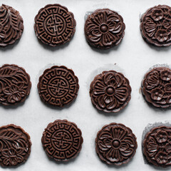 Overhead view of stamped chocolate cookies on a parchment lined baking tray, top view of embossed chocolate sugar cookies on a white background