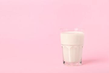 Glass of milk on pink background