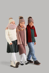 Fototapeta premium Cute little happy kids in warm clothes on grey background