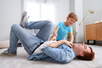 Little boy tickling his father at home