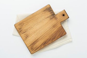 Cutting board with napkin on color background, top view