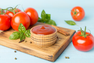 Delicious ketchup with spices and tomatoes on wooden table