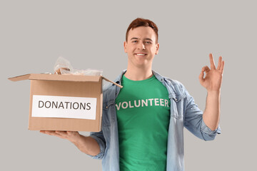 Male volunteer with donation box showing OK on light background