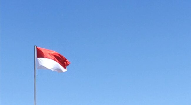 Surabaya - Indonesia, August 6, 2024.
The Indonesian Red and White flag flies in the clear blue sky, in celebration of the 79th Independence Day of the Unitary State of the Republic of Indonesia.