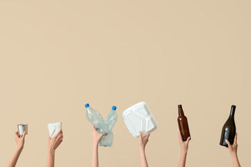 Female hands holding different litter on beige background. Recycling concept