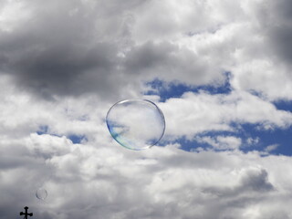 soap bubbles in the sky and a christian cross at the bottom