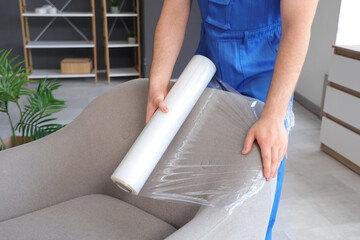 Loader covering furniture with polyethylene film in room, closeup