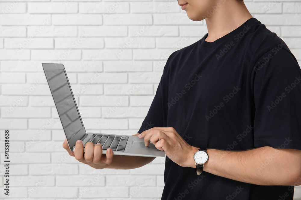 Wall mural male programmer using laptop on white brick background