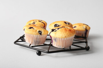 Cooling rack with tasty blueberry muffins on white background, closeup