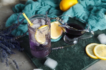 Glass of cold lavender lemonade, syrup, lemons and flowers on grunge table