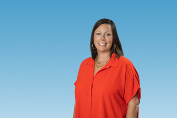 Headshot of Caucasian brunette middle age business woman in studio on blue backdrop with copy space