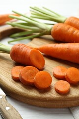 Whole and cut fresh carrots on white wooden table, closeup