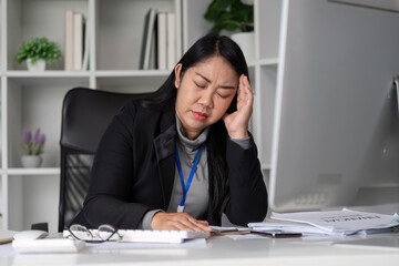 Stressed Business Woman Working at Computer in Modern Office, Experiencing Fatigue and Overwhelm