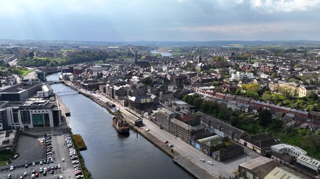 Drogheda, County Louth, Ireland, April 2023. Drone pushes forward, over the Boyne River with the Urban cityscape towards a street view with light traffic on a sunny day.