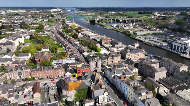 Drogheda, County Louth, Ireland, April 2023. Drone rotates clockwise around St Laurence's Gate surrounded by the urban rooftops of buildings and houses with the Boyne Viaduct in the background.