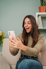 Vertical woman celebrating that she has won a sports bet while checking the result on a smartphone...