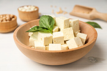 Tofu in a wooden bowl with leaves on a light background