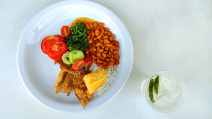 Traditional brazilian meal known as prato feito and a cup with sparkling water with some lemon slices on the white background with copy space.
