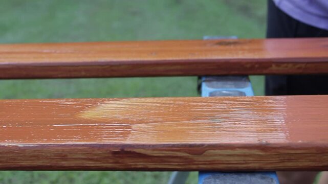 Slow Motion shot Following a Woman Applying a Coat of Paint to a Decking Board Outside