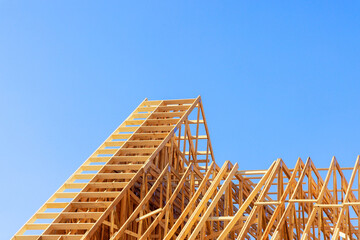 Obraz premium Installation beams of wooden roof trusses to house under construction