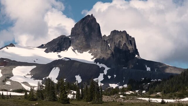 Large clouds moving behind mountain peak on a sunny day