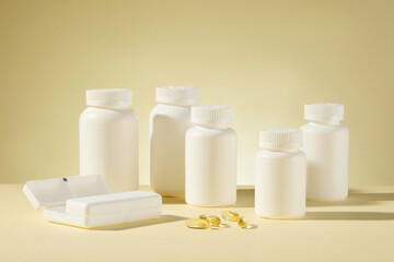 Several white mockup bottle without label neatly arranged on the table and featured on light yellow background, with a white pill box and some soft yellow supplement capsule flat lay on the table